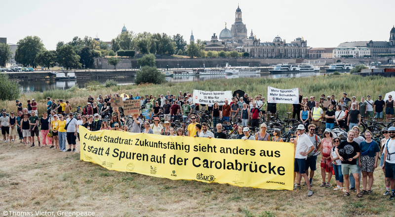DresdenZero fordert mit Bündnispartnern auf einem Transparent zwei statt vier Spuren für Carolabrücke. Zur Kundgebung sind viele Menschen gekommen